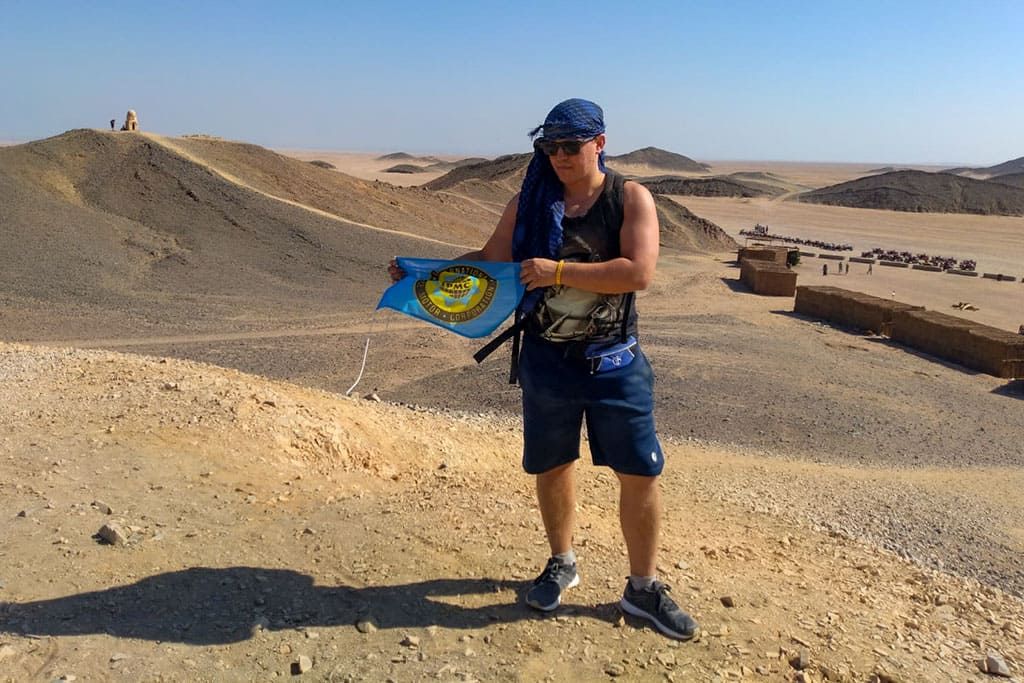 Tim Meier mit der IPMC Flagge in der Sahara